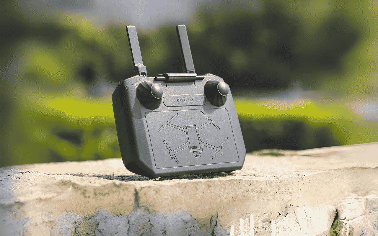 Auf dem Bild liegt ein DJI RC Pro Controller mit Sonnenblende auf einer Mauer.