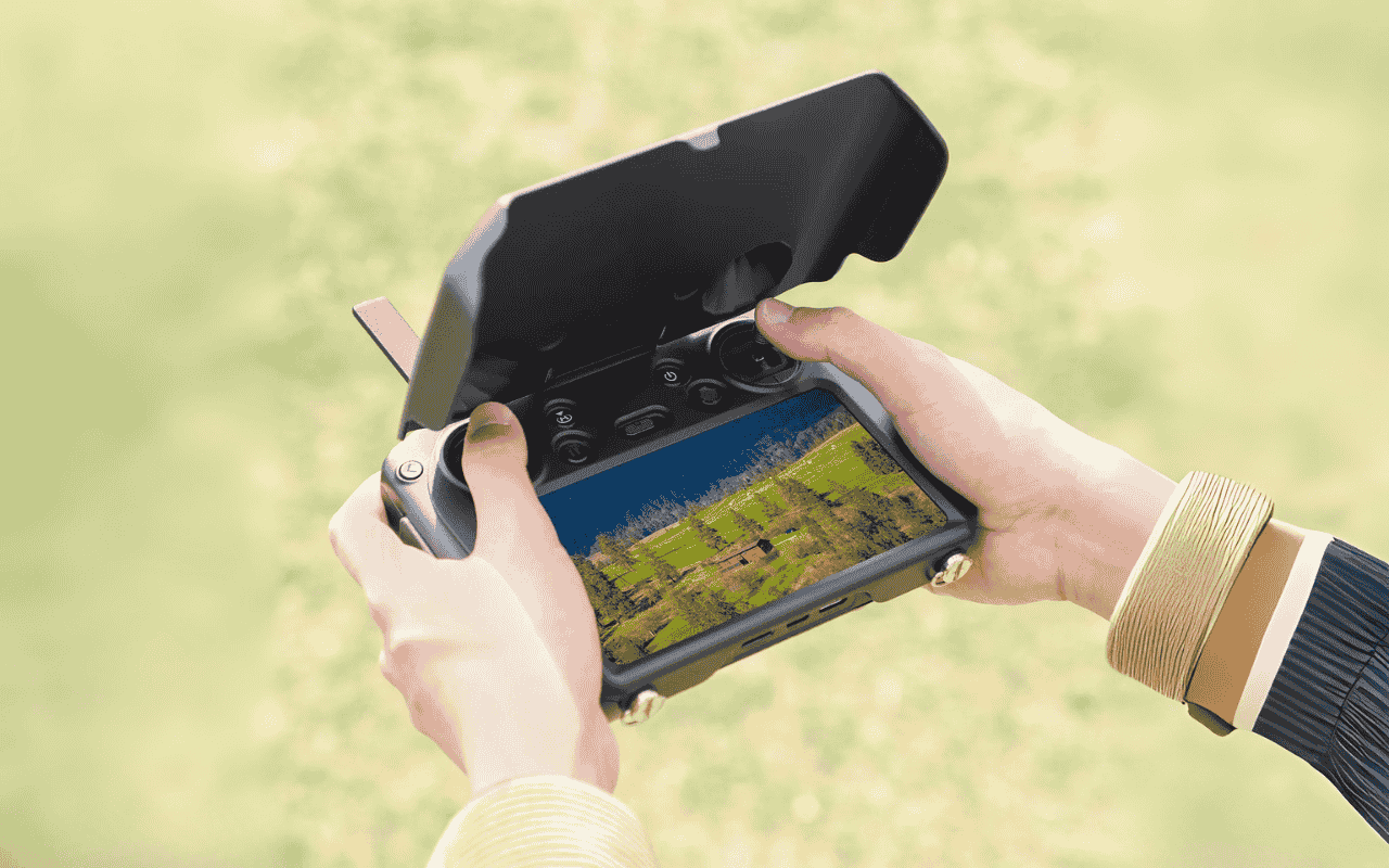 Auf dem Bild hält eine Person den DJI RC Pro Controller, ausgestattet mit einer Sonnenblende, in der Hand.