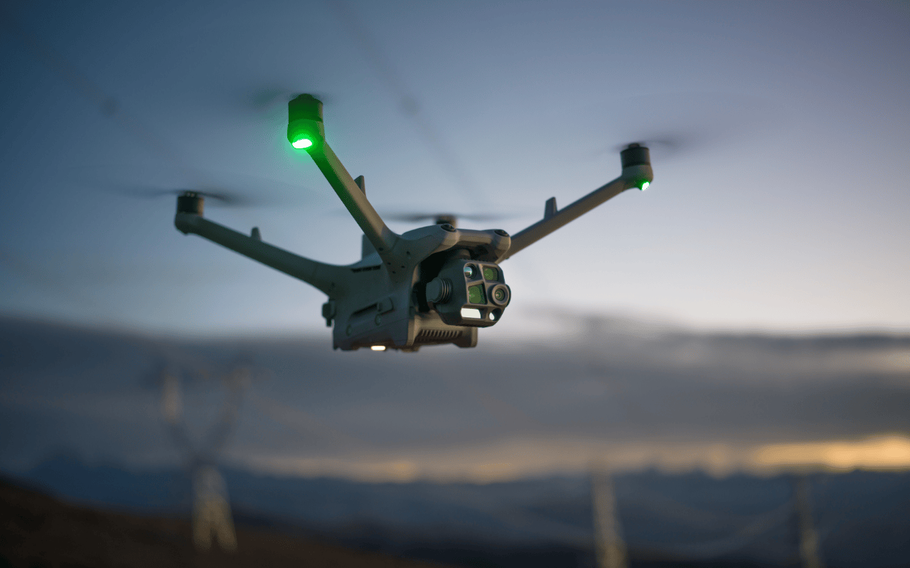 Auf dem Bild ist die DJI Matrice 4TD Drohne während eines Inspektionfluges entlang von Hochspannungsleitungen zu sehen.  