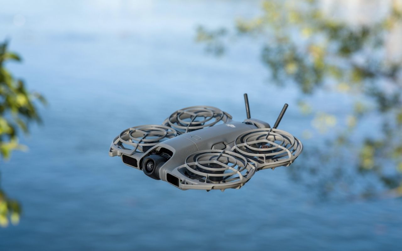 Auf dem Foto ist eine fliegende DJI Neo 2 Drohne über einem Gewässer zu sehen. 