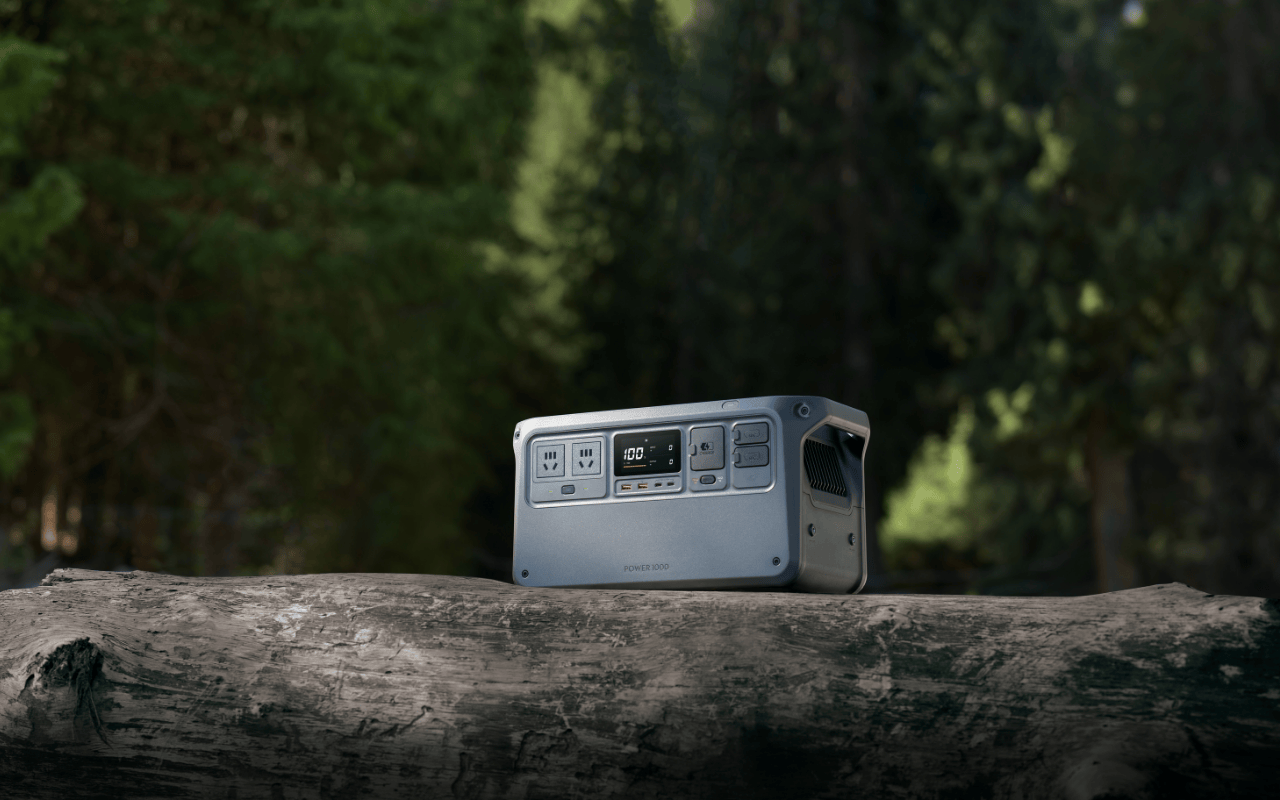 Auf dem Bild ist die DJI Power 1000 Powerstation in der Natur auf einem Baumstamm zu sehen.