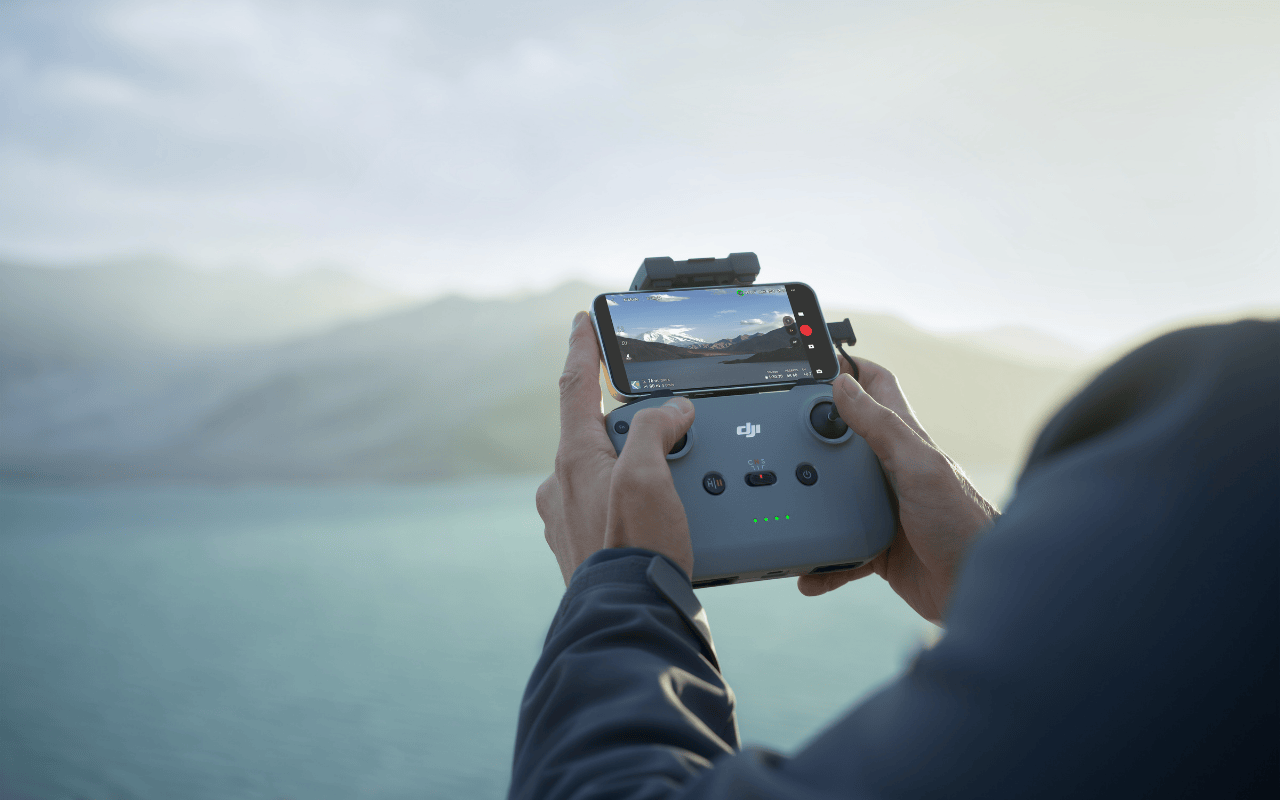 Auf dem Foto hält eine Person den DJI RC-N3 Controller in der Hand und steuert mit diesem eine Drohne. 
