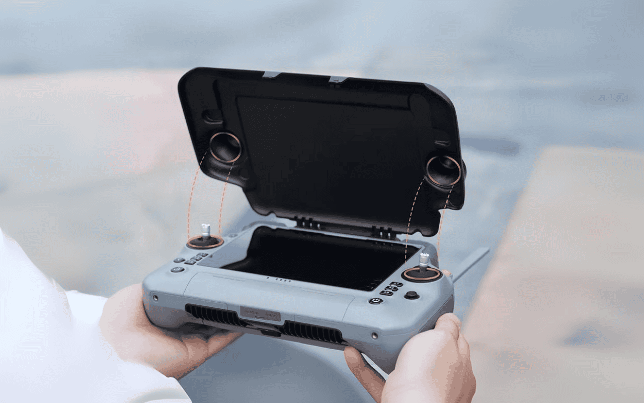 Auf dem Bild hält eine Person den DJI RC Plus Controller, ausgestattet mit einer Sonnenblende, in der Hand.