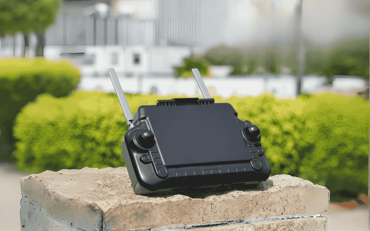 Auf dem Bild liegt ein DJI RC Plus Controller mit Sonnenblende auf einer Mauer.